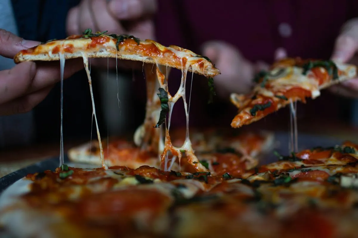 Meleg pizzáról nyúló olvasztott sajt