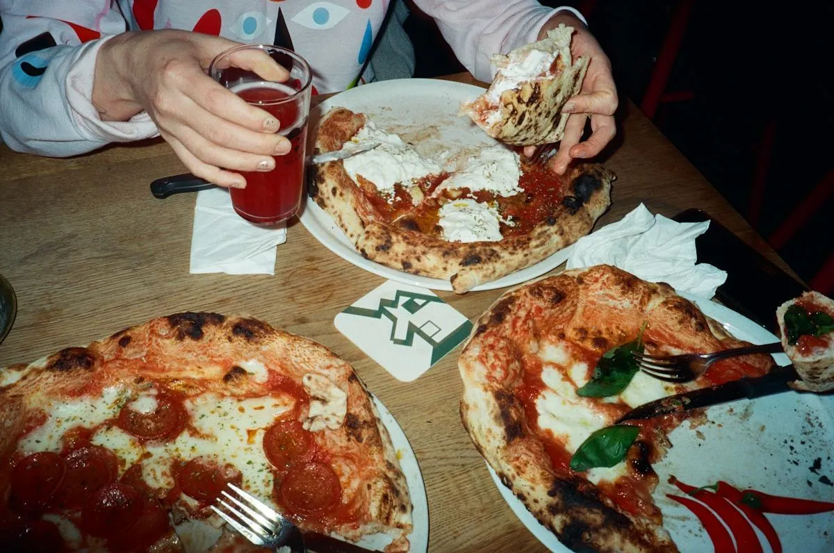 Pizzát szeletelő vendégek közös étkezése